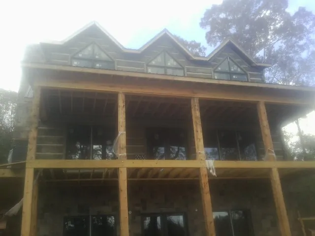 Dormers and porch framing on a large log home under construction — Roof Coating work by our crew in Meeker