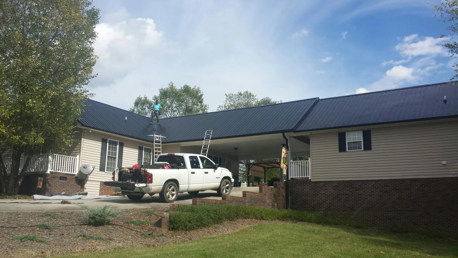 Black metal roof over a home and attached breezeway with ladders set in Meeker