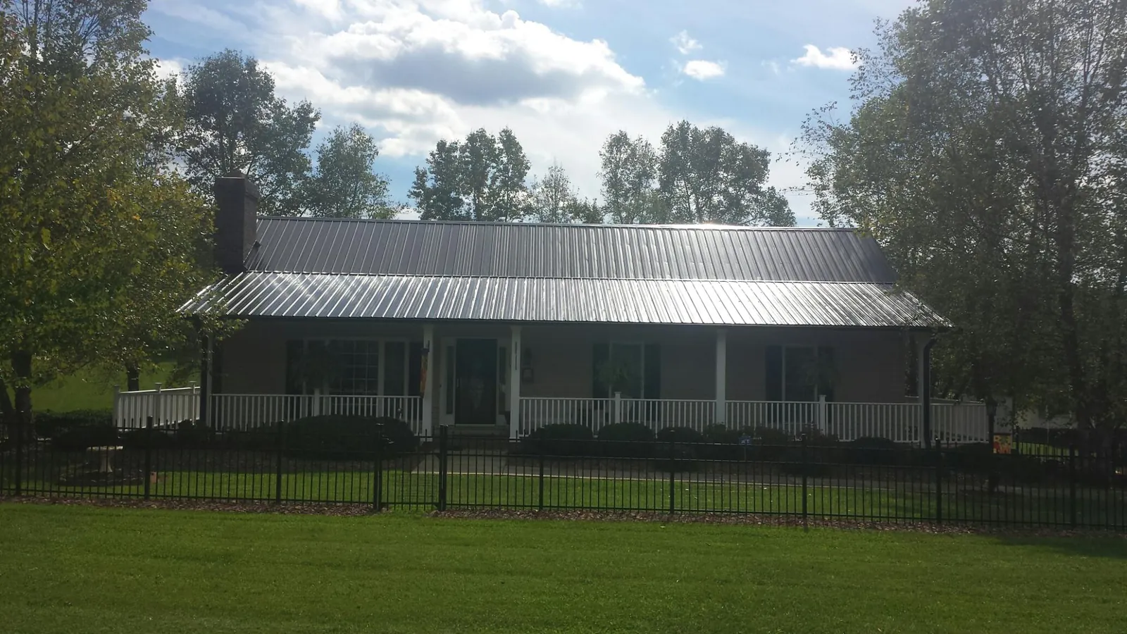 Gray metal roof on a brick ranch with a full width front porch — Gutter Guard Installation work by our crew in Meeker
