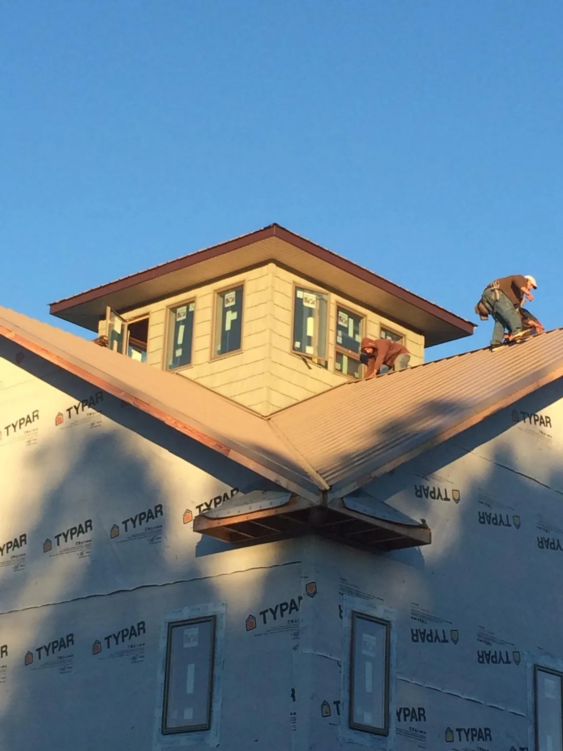 Roofers working around a rooftop cupola on a new metal roof at sunset — Roof Waterproofing in Meeker by Roofing Brothers